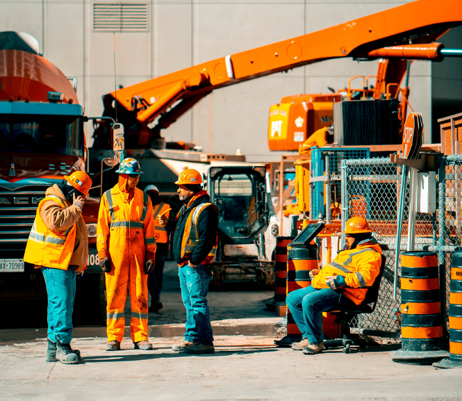four construction workers talking in front of equipment